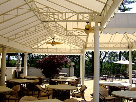 a white stationary awning structure providing shade by a pool